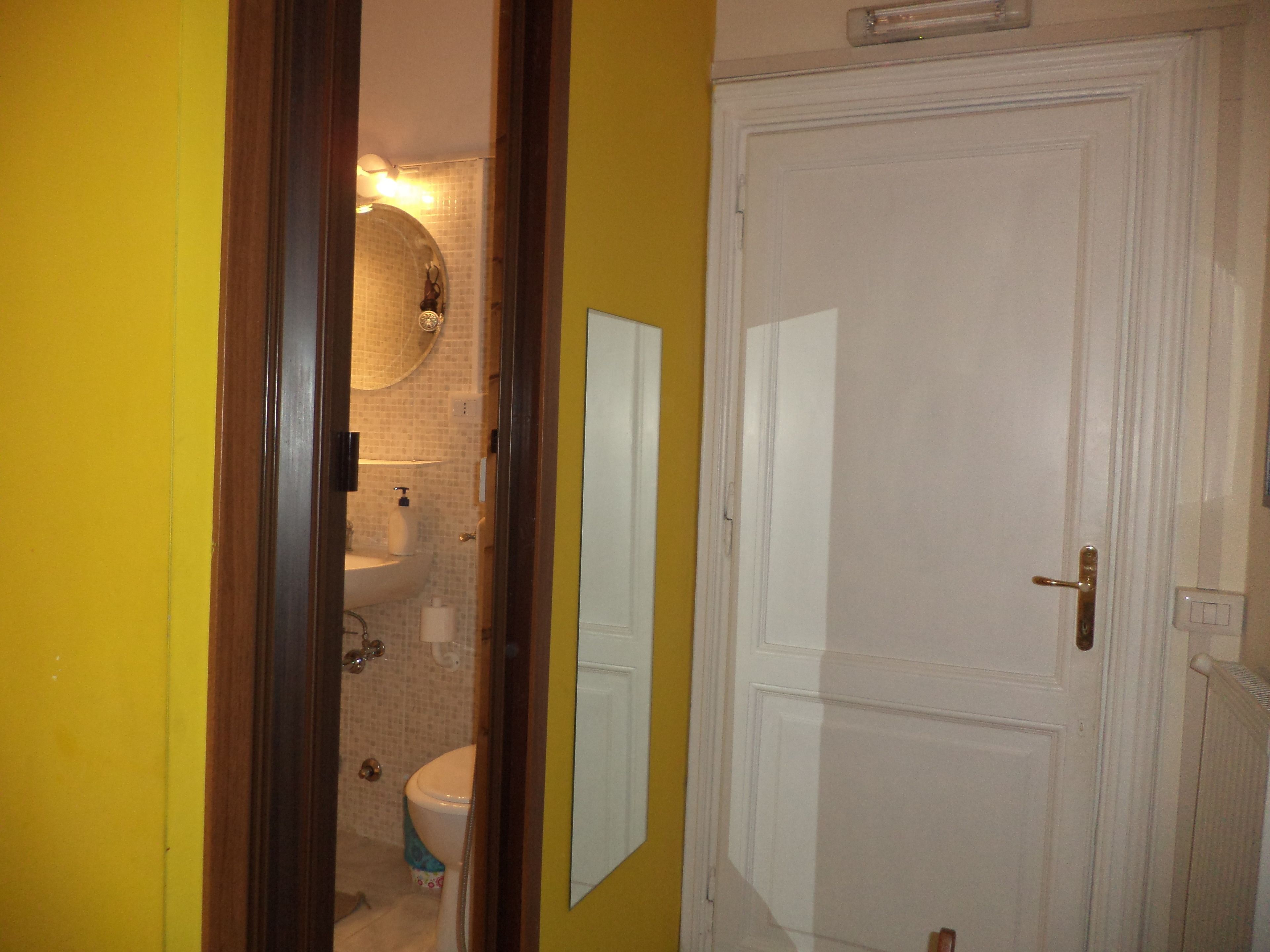A bathroom with a toilet, sink, and mirror.