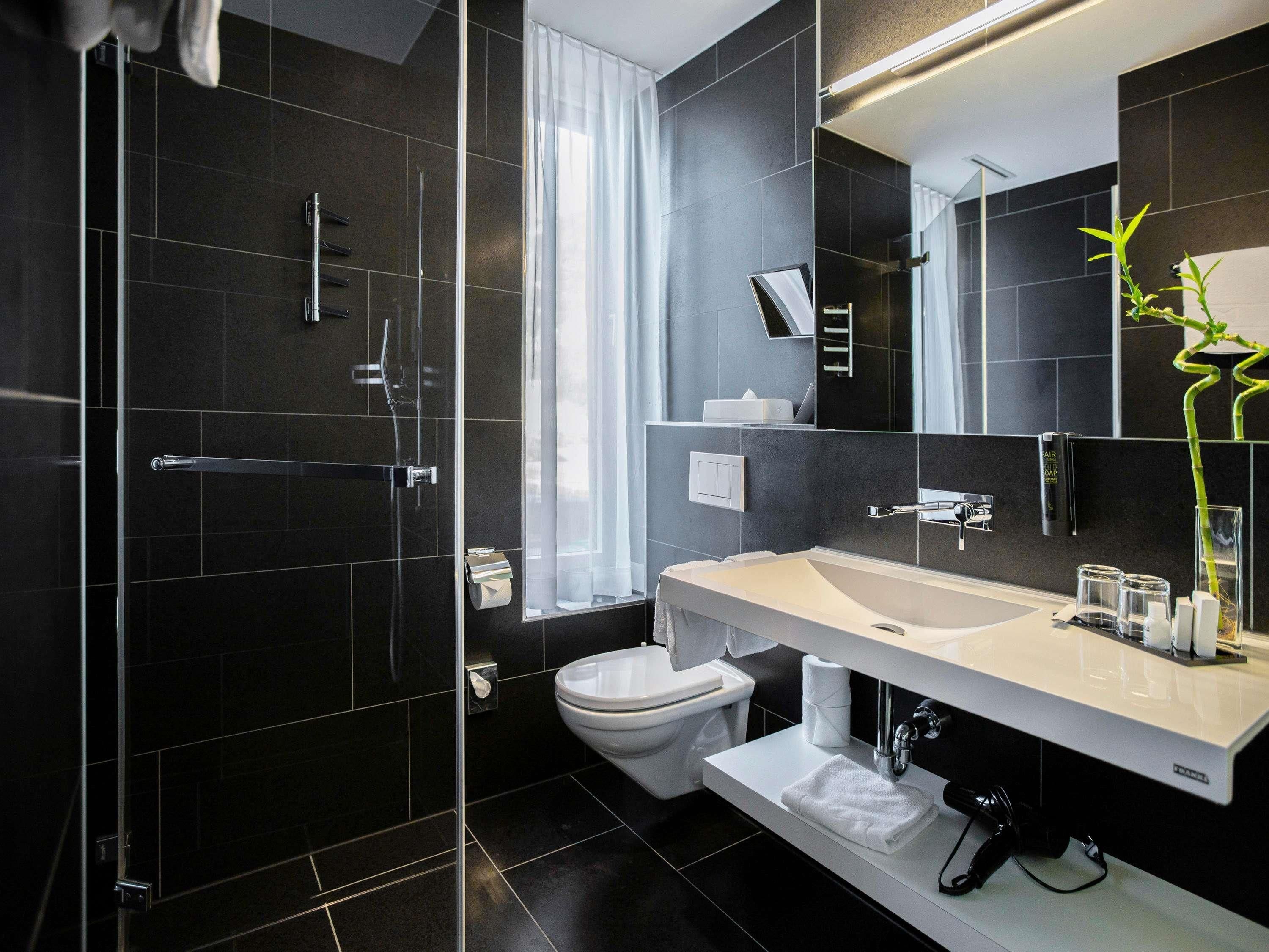 A modern bathroom with a glass-enclosed shower, a white sink, and a large mirror.