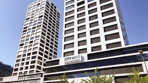 A modern hotel with a grid-like facade, multiple floors, and a sign indicating it is a hotel and restaurant. - Mercure Chur City West (Chur)