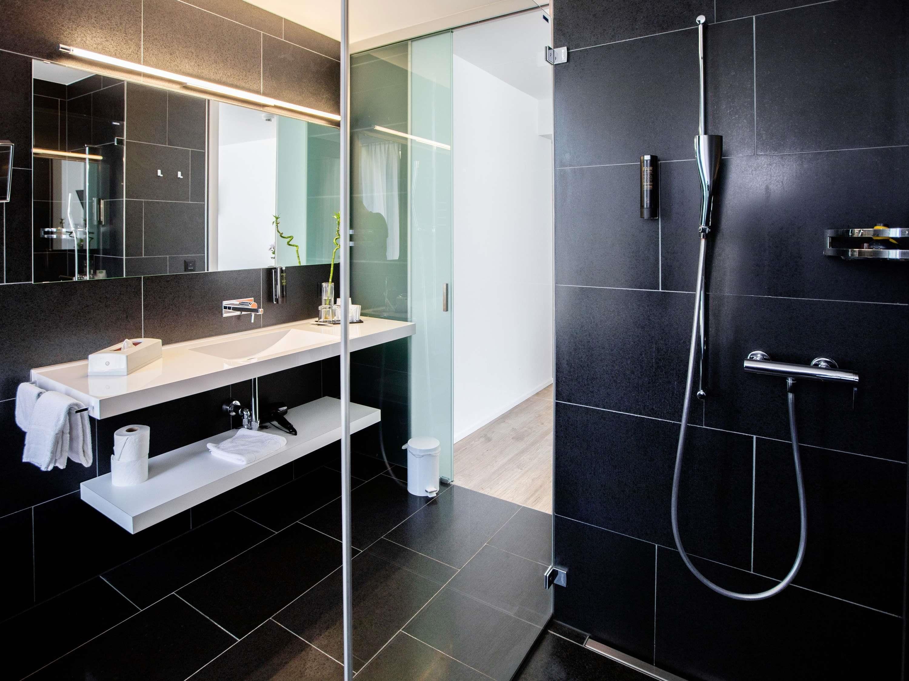 Une salle de bain moderne avec une douche à parois de verre, un lavabo blanc et un miroir.