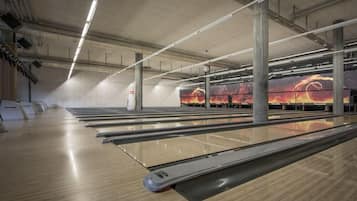 Bolera con múltiples pistas, suelos de madera e iluminación suspendida.