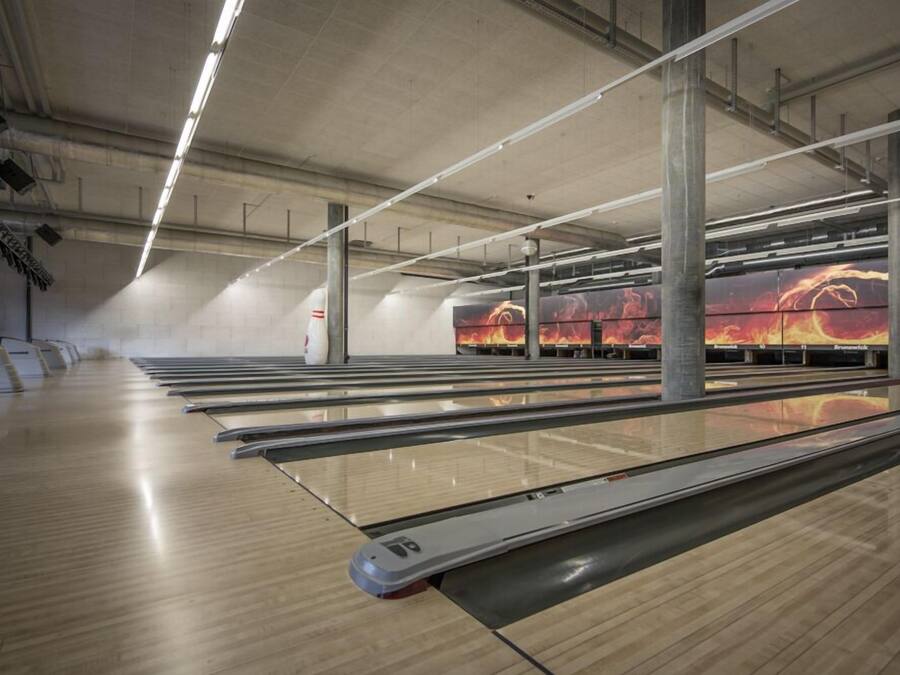 Bolera con múltiples pistas, suelos de madera e iluminación suspendida.
