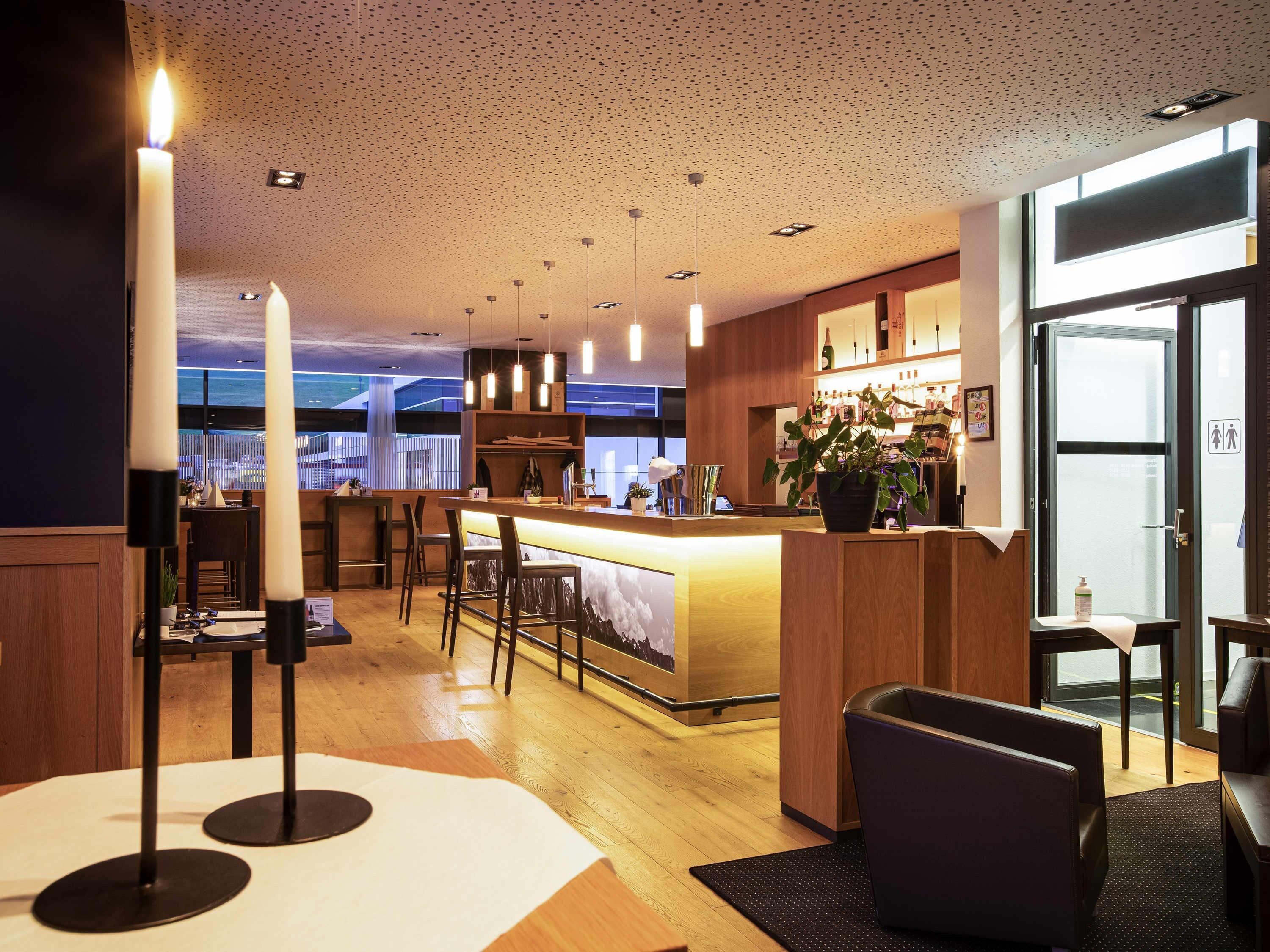 A modern hotel lobby with a bar area, seating, and a view of the sea.