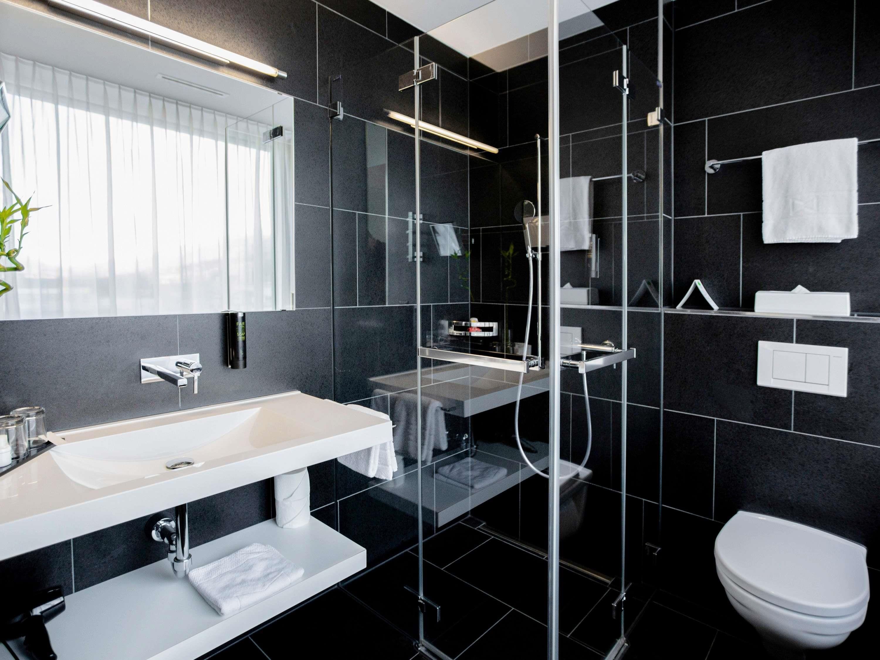 A modern bathroom with a glass-enclosed shower, a white sink, and a toilet.