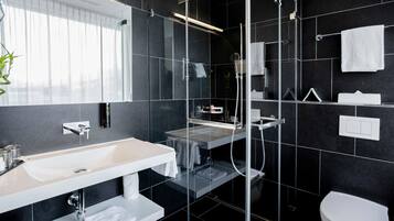 A modern bathroom with a glass-enclosed shower, a white sink, and a toilet.