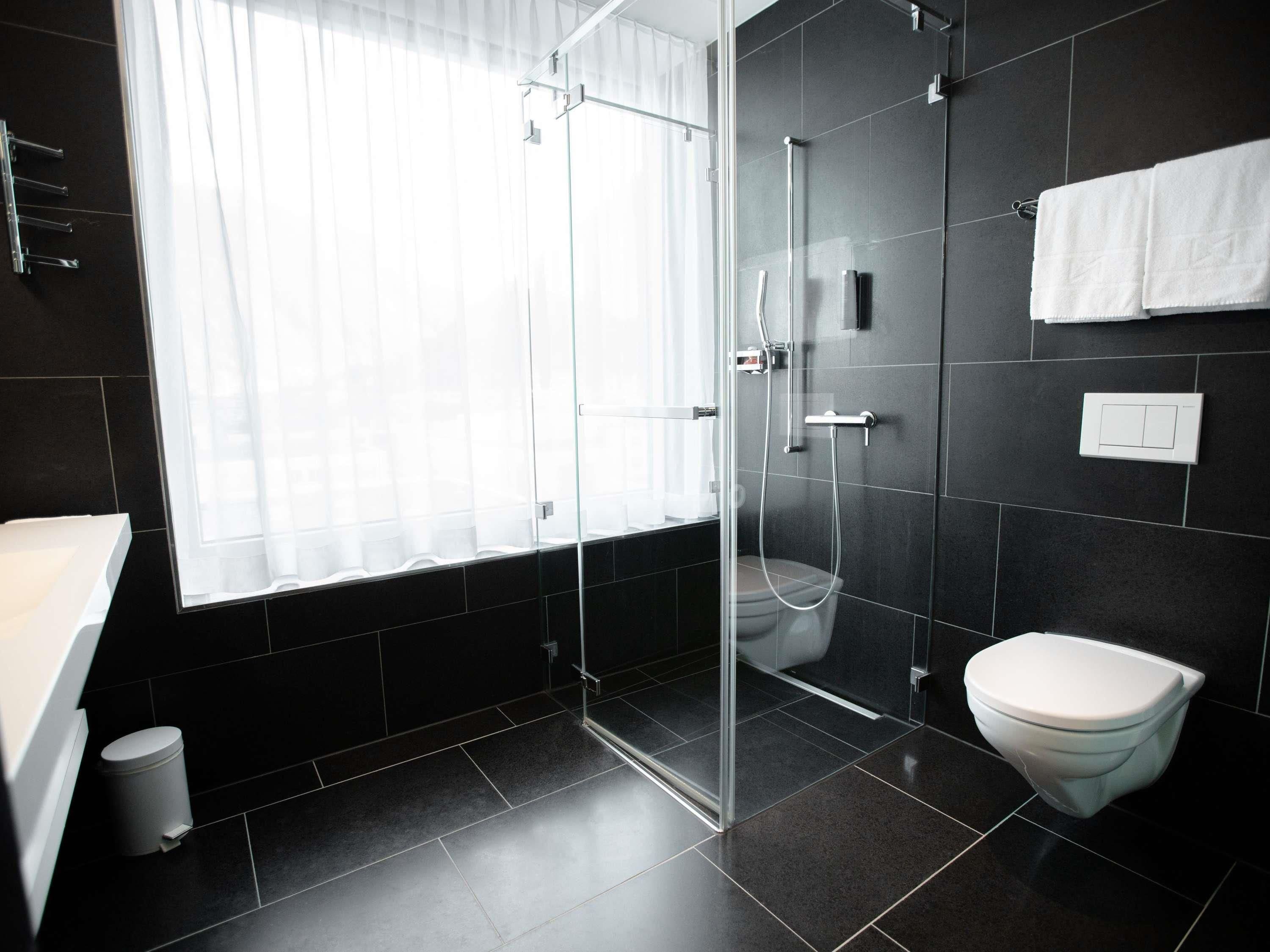 Un bagno moderno con box doccia in vetro, un water e un lavandino.