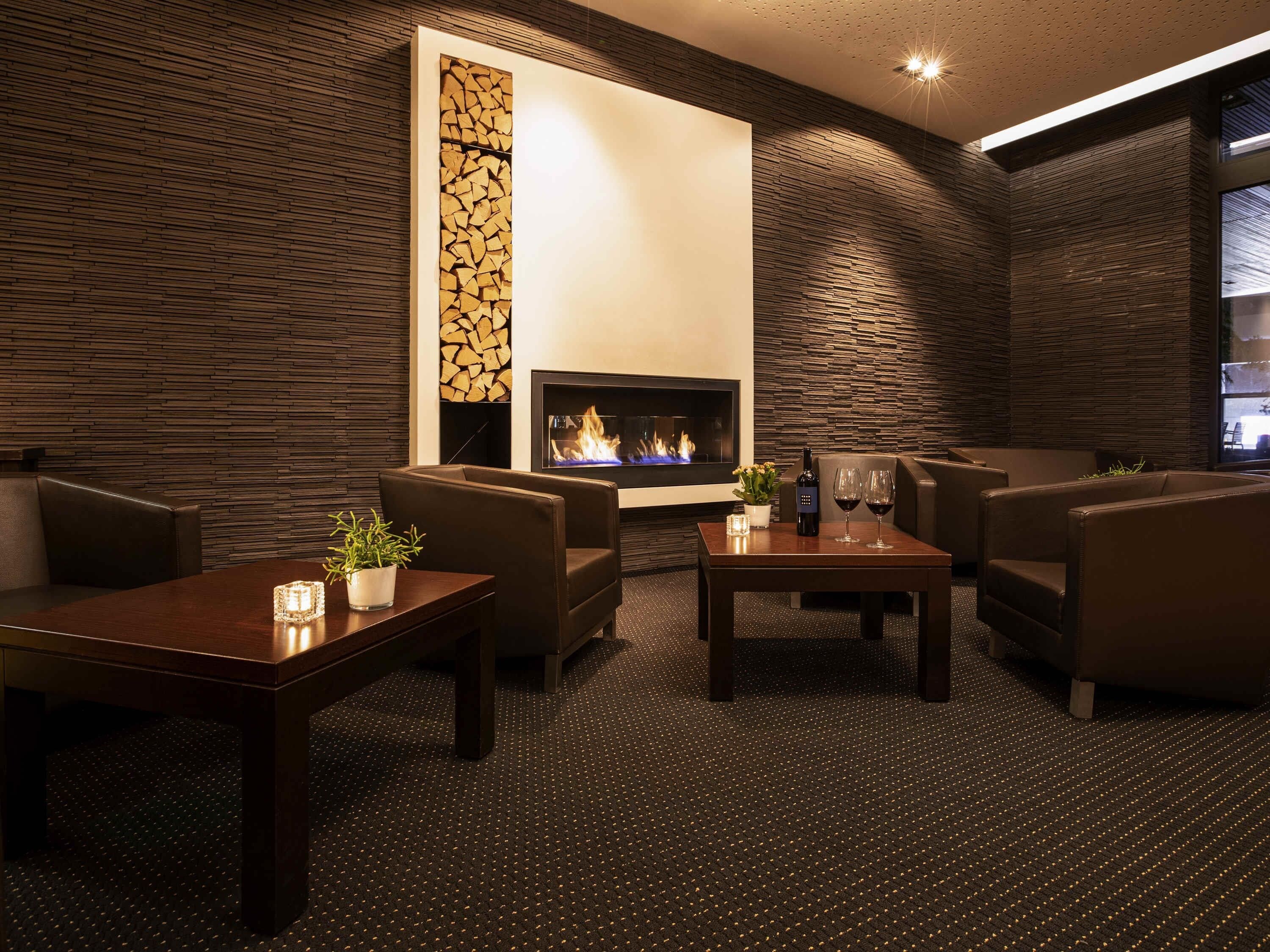 A modern lounge area with leather seating, a fireplace, and a patterned wall.
