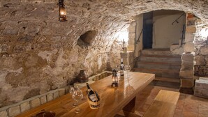 A rustic cellar with a wooden table set for wine tasting, stone walls, and a staircase leading upstairs. - Apartmán-Hotel Jítrava (Rynoltice)