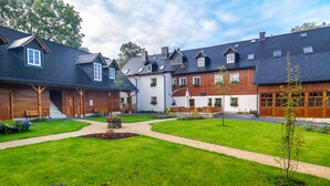 A courtyard with a central pathway, surrounded by wooden buildings with multiple windows and doors. - Apartmán-Hotel Jítrava (Rynoltice)