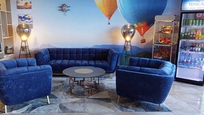 Un espacio lounge moderno con un sofá seccional azul, una mesa redonda de centro y dos lámparas de pie.