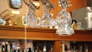 A bar with hanging wine glasses and a decorative figure.