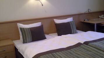 A hotel room with a bed, bedside table, lamp, and a painting on the wall.
