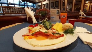 Una mesa con un plato de comida, un vaso de jugo de naranja y una servilleta.