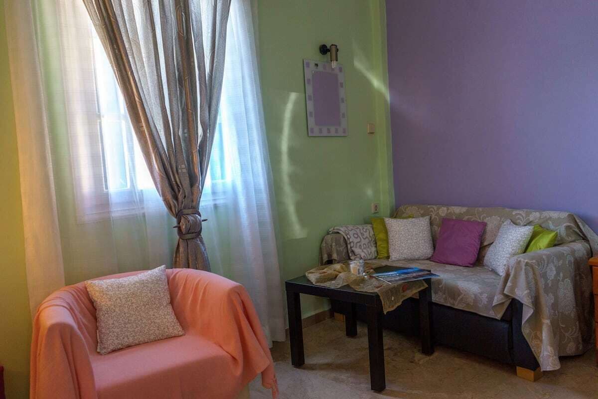 A living room with a sofa, a chair, a table, and a window with curtains.