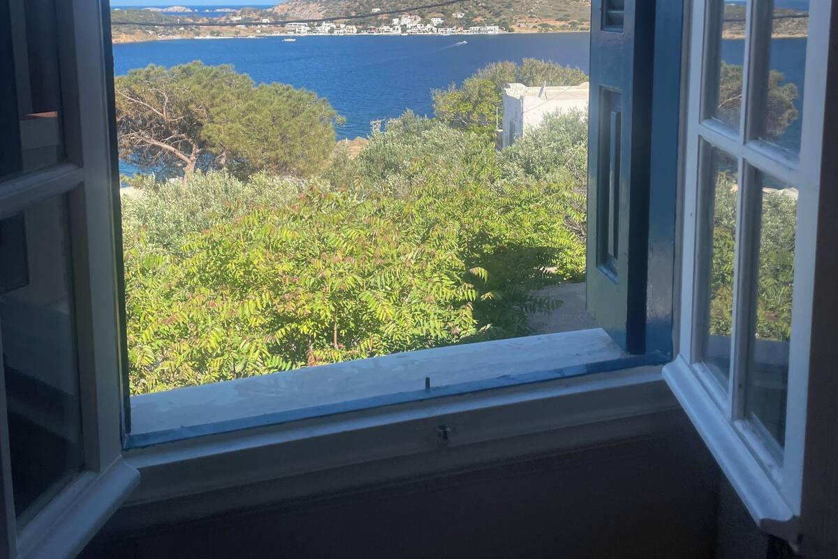 Ein Fenster mit freiem Blick auf eine Küstenlandschaft, einschließlich eines Gewässers, eines Berges und viel Grün.