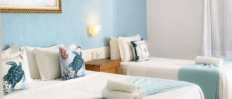 Habitación de hotel con dos camas, aire acondicionado en la pared y una ventana con cortinas.