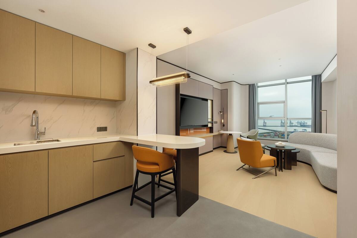 Una cocina moderna con barra, comedor y sofá en una sala de estar con ventana grande.