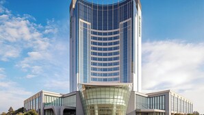 Un immeuble moderne de grande hauteur, doté d’une façade incurvée en verre et d’une conception symétrique.