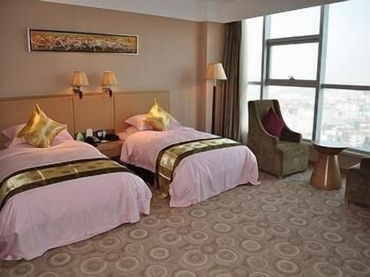 Ein Hotelzimmer mit zwei Betten, einem großen Fenster und Blick auf die Stadt.