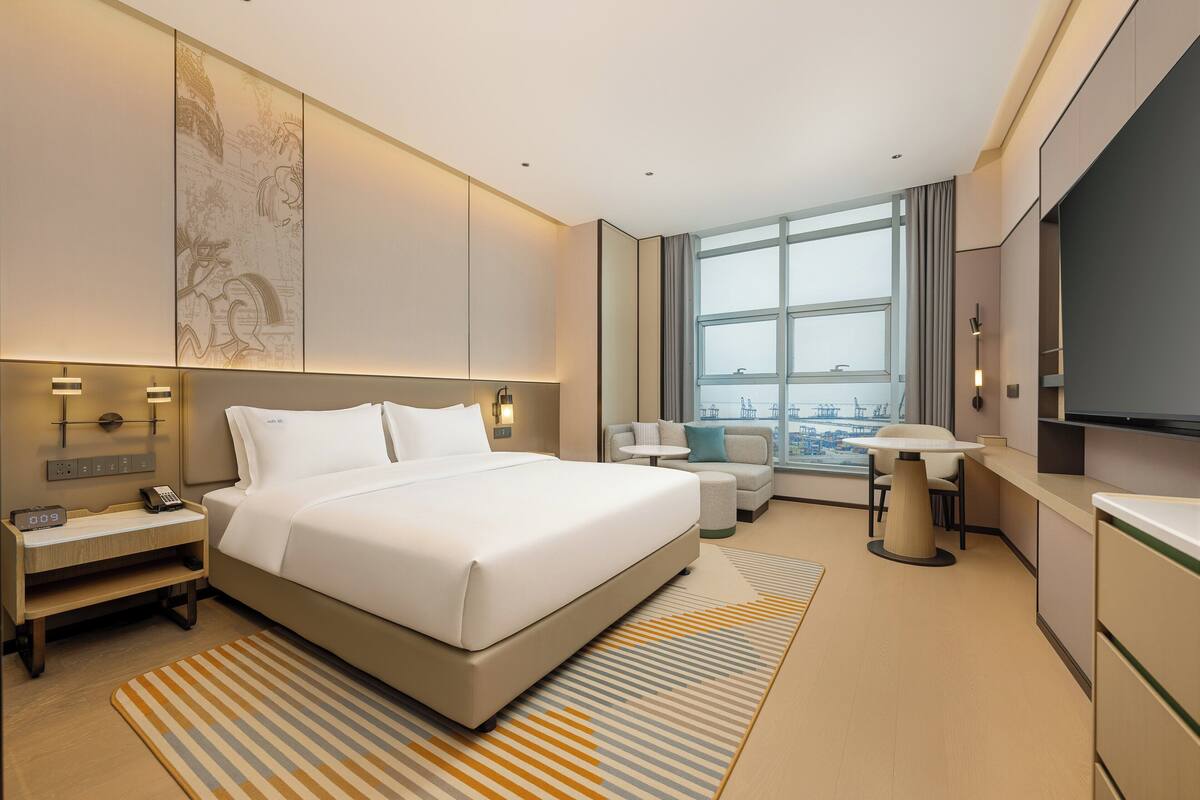 Una habitación de hotel moderna con una cama grande, un escritorio, un sofá y un televisor.