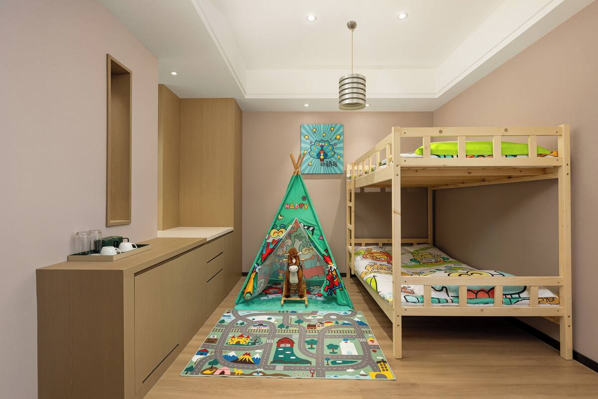 Habitación infantil con literas, un escritorio, una tienda de juegos y un tapete colorido.