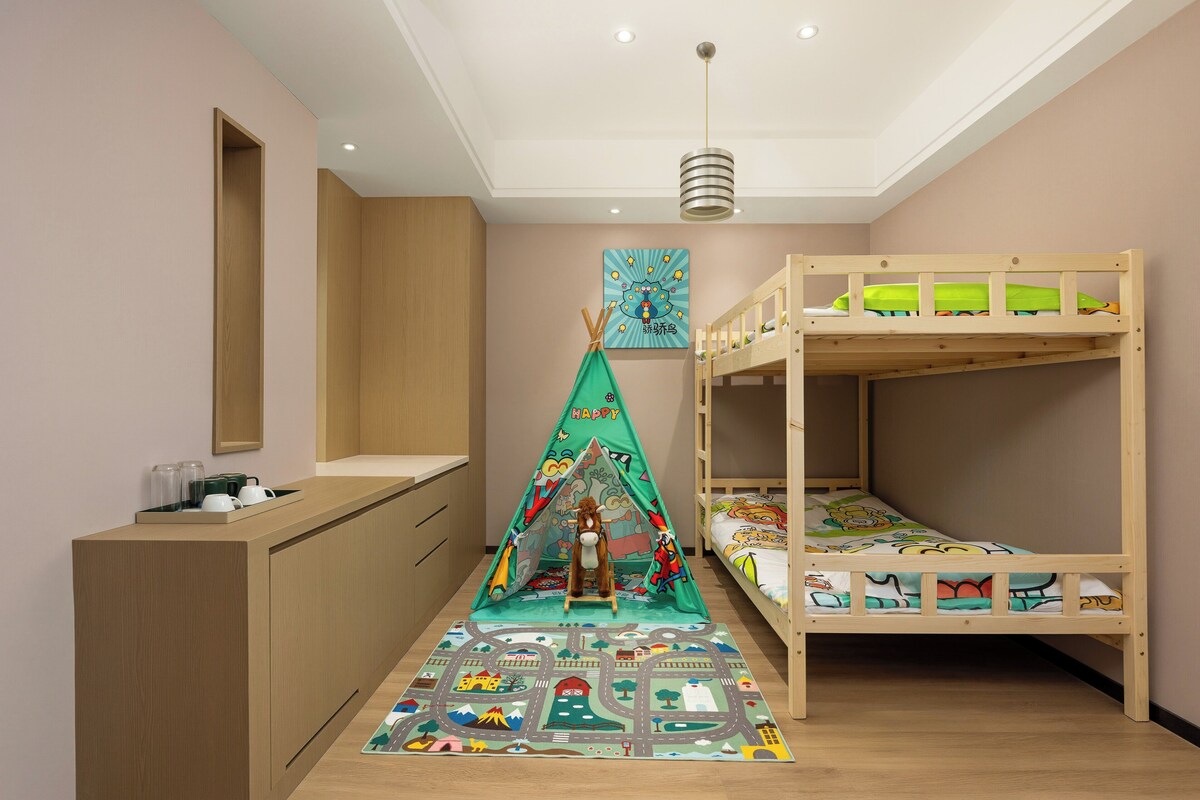 Habitación infantil con literas, un escritorio, una tienda de juegos y un tapete colorido.
