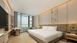 Une chambre d’hôtel moderne dotée d’un grand lit, d’un bureau, d’un canapé et offrant une vue sur la ville.
