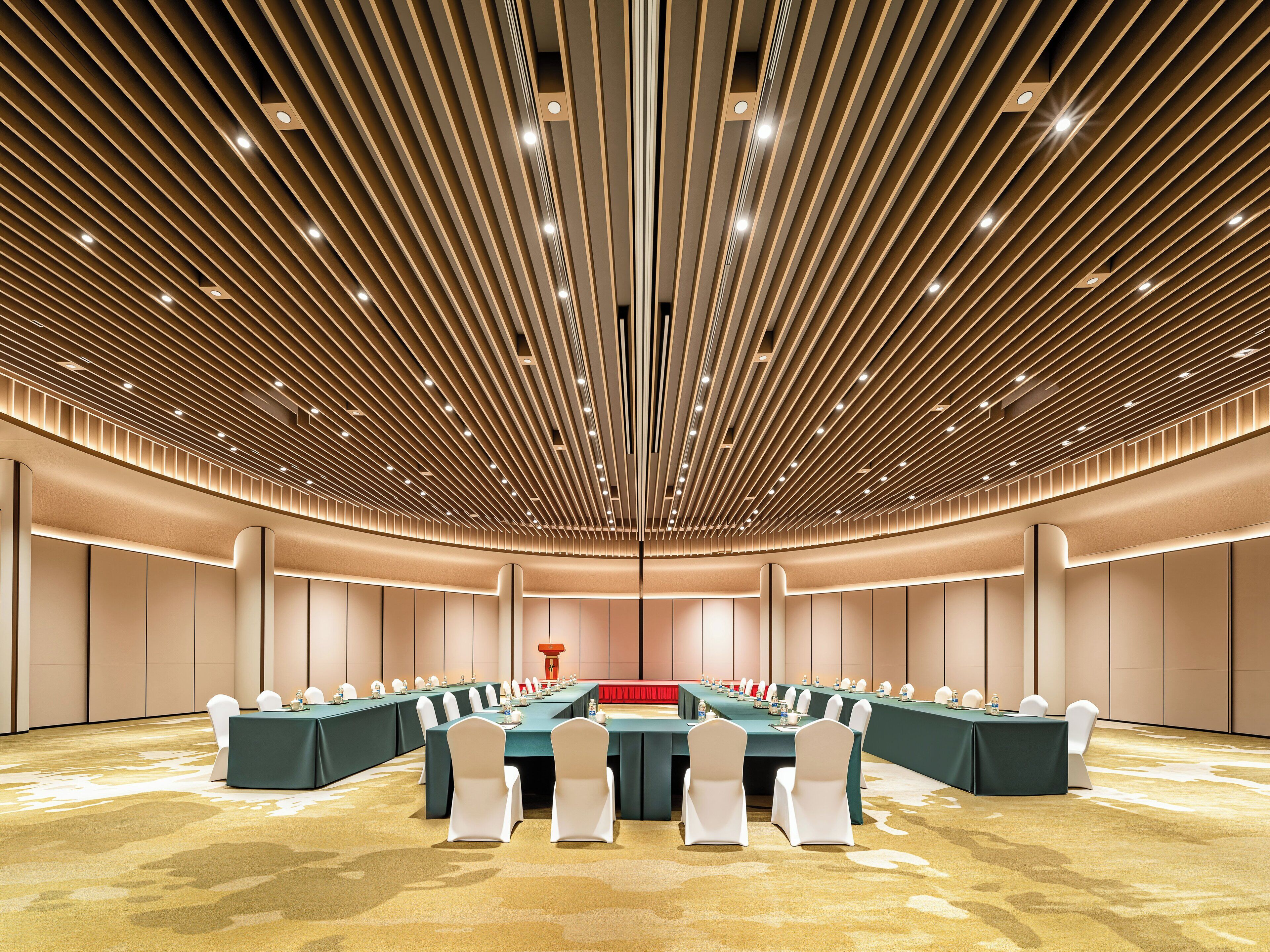 A conference room with a long table, white chairs, and a modern ceiling design.