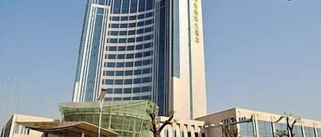 A modern hotel with a curved facade, large windows, and a covered entrance area.