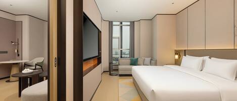 Une chambre d’hôtel moderne équipée d’un grand lit, d’une télévision, d’un canapé et d’un coin repas.