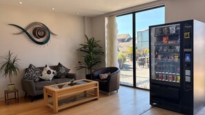 A modern living room with a sofa, coffee table, and a large window. - Liberty Wharf Apartments (St. Helier)