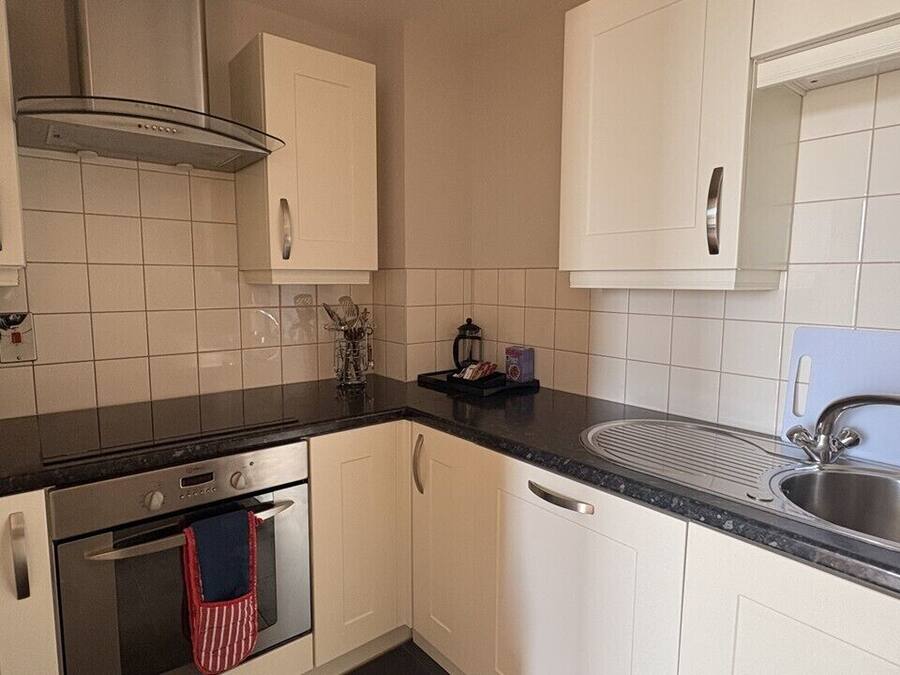 A kitchen with white cabinets, a stainless steel sink, and a window.