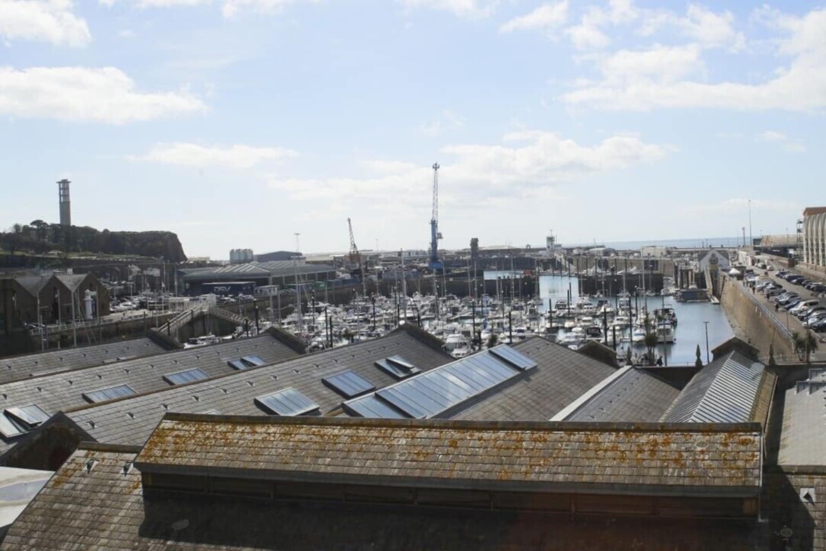 A marina with boats, a lighthouse, and industrial buildings.