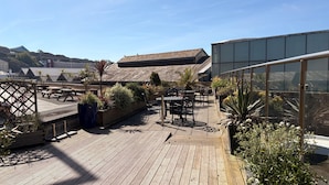 A rooftop patio with wooden decking, outdoor seating, and potted plants. - Liberty Wharf Apartments (St. Helier)