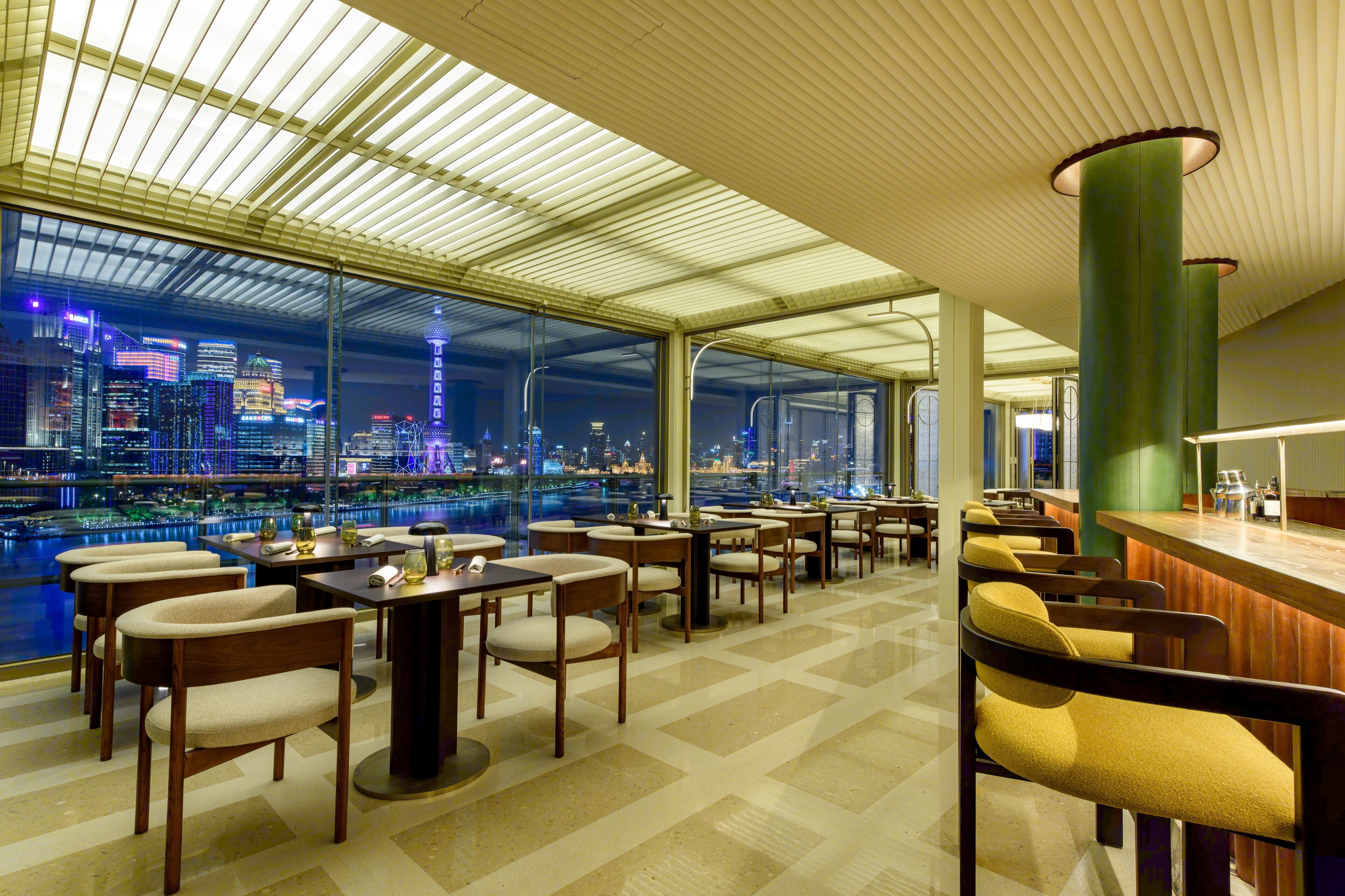 A modern restaurant with a view of a city skyline at night.