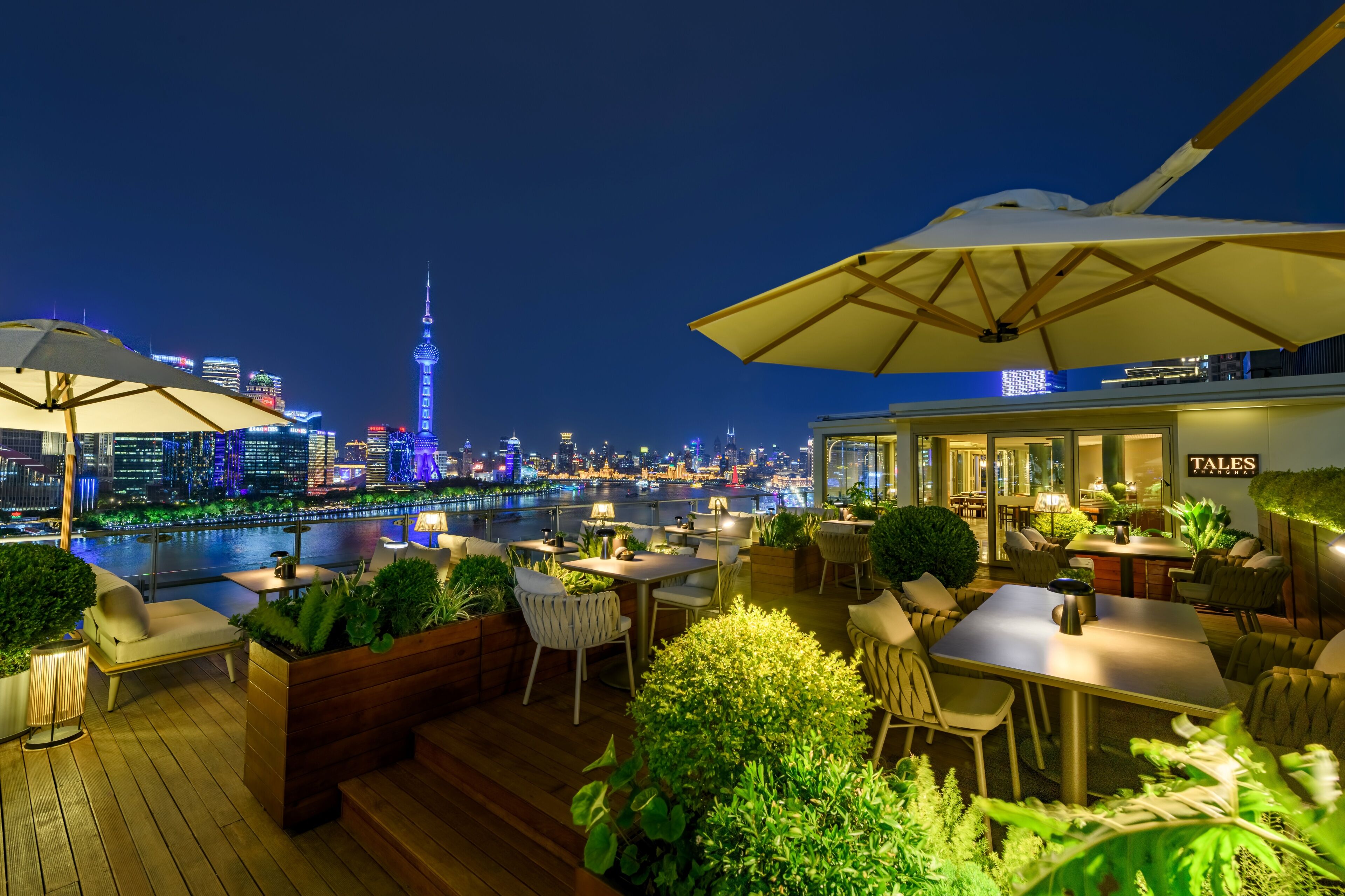 Una terraza en la azotea con mobiliario exterior, vistas del horizonte urbano y un restaurante llamado 'Tales'.
