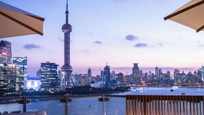 A rooftop terrace with a view of a city skyline, including a prominent tower, and a sign that reads "TAIL SHANG". - Banyan Tree Shanghai On The Bund (Shanghai)