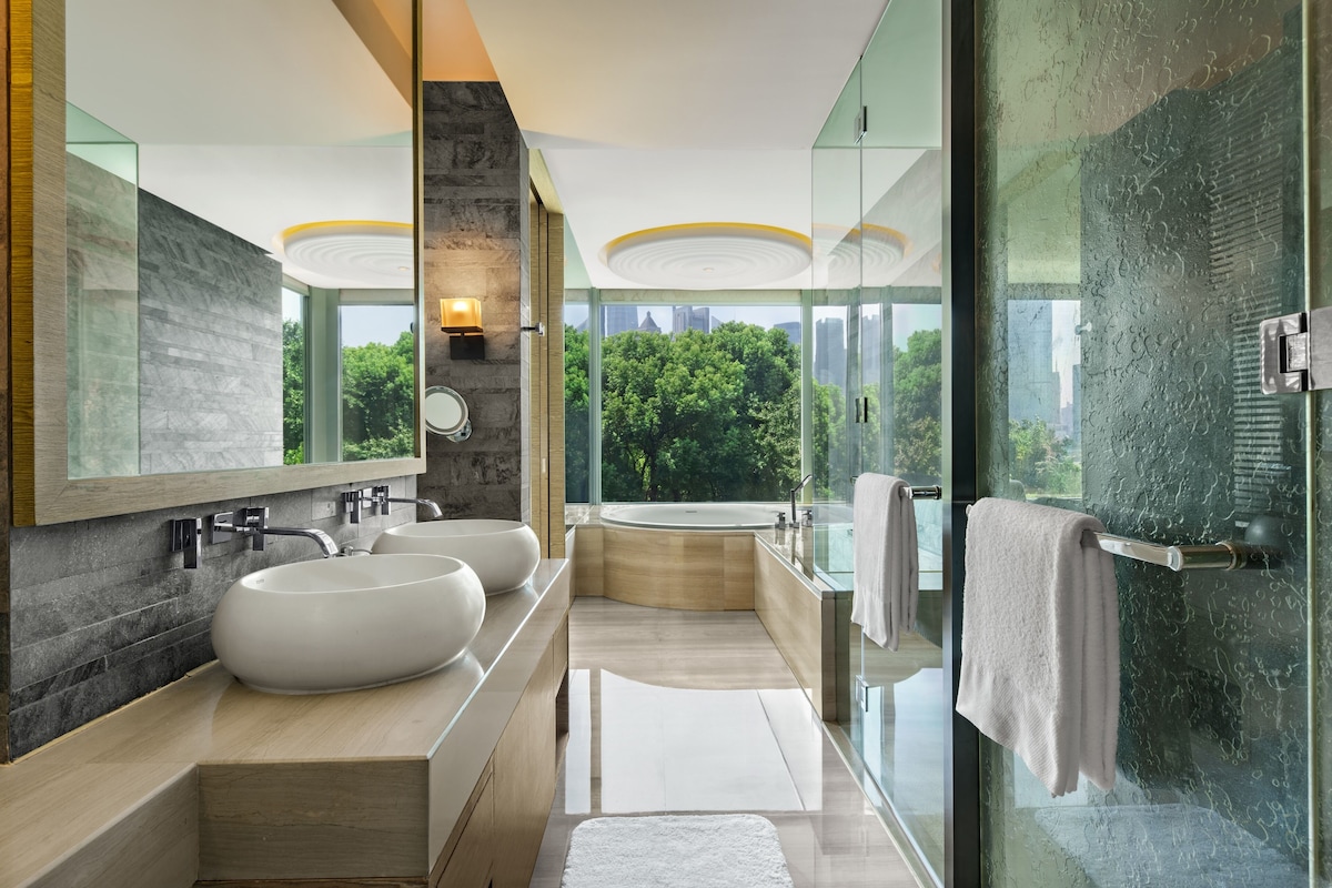 A modern bathroom with two large sinks, a bathtub, and a glass shower enclosure.