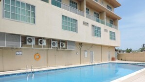 A swimming pool adjacent to a building with air conditioning units, a lifebuoy, and a sign indicating no smoking. - Mayfair Hotel (Dar es Salaam)