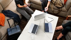 A modern living room with a sofa, two laptops, a tablet, a suitcase, and a coffee table. - Hyatt Place Austin Downtown (Austin)