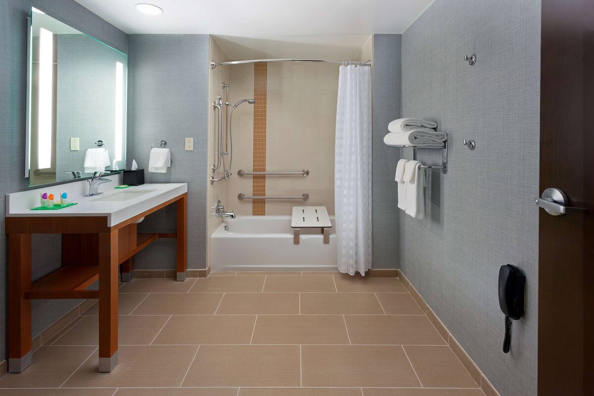 A modern bathroom with a sink, mirror, shower, and toilet.
