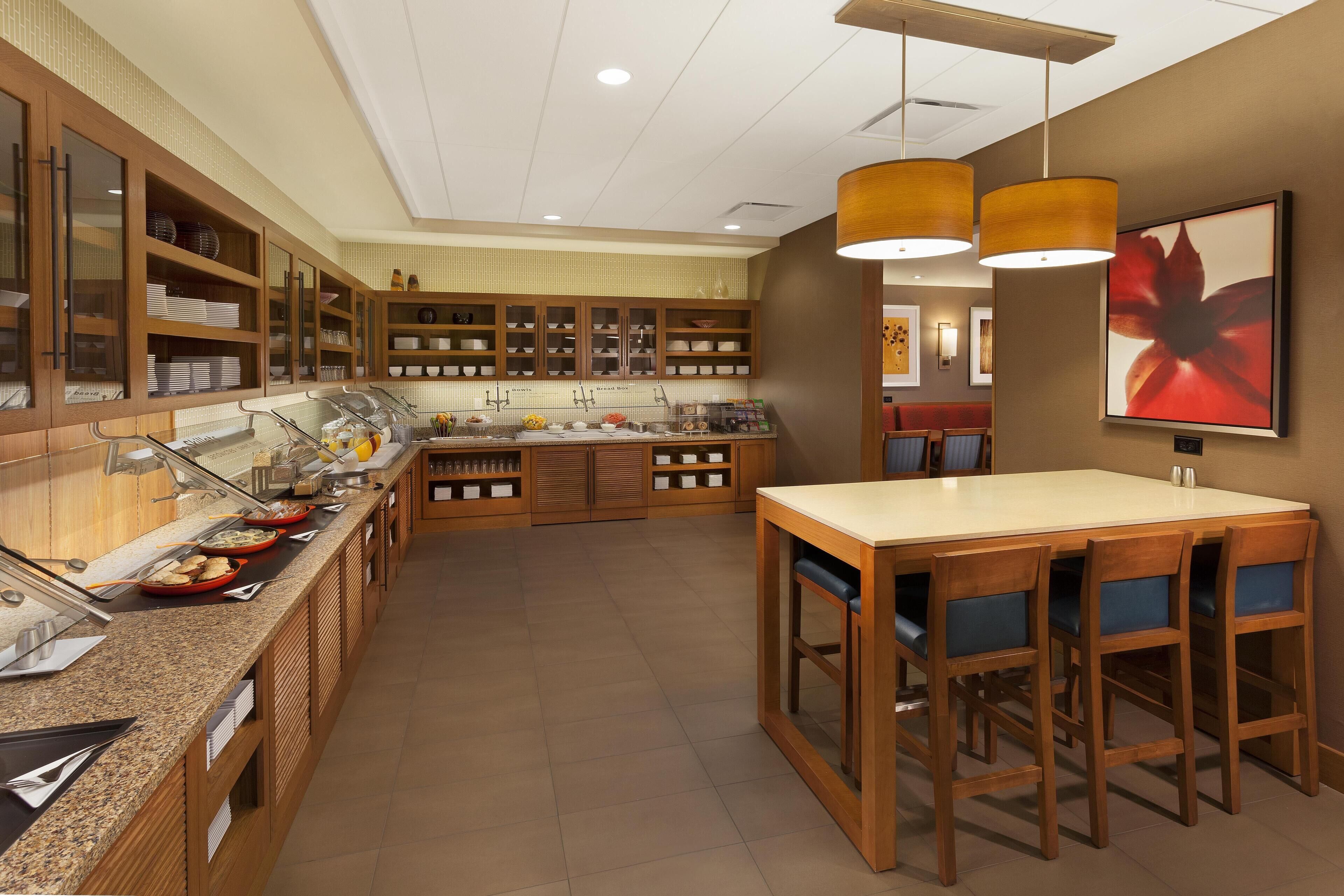 Une cuisine moderne avec un espace buffet, des meubles de rangement en bois et un coin repas comprenant une table et des chaises.