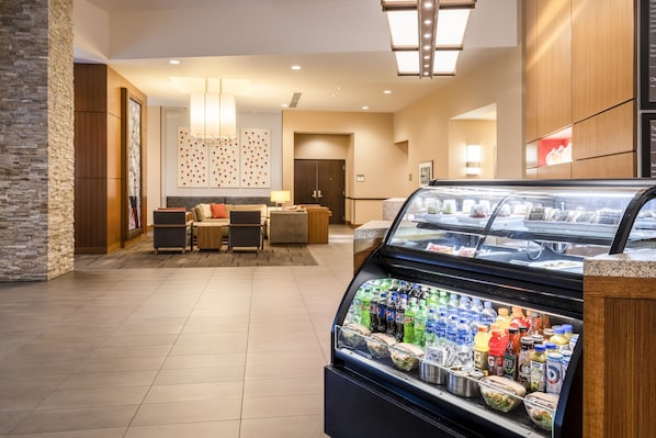 A hotel lobby with a seating area, a refreshment display, and a reception desk. - Hyatt Place Austin Downtown (Austin)