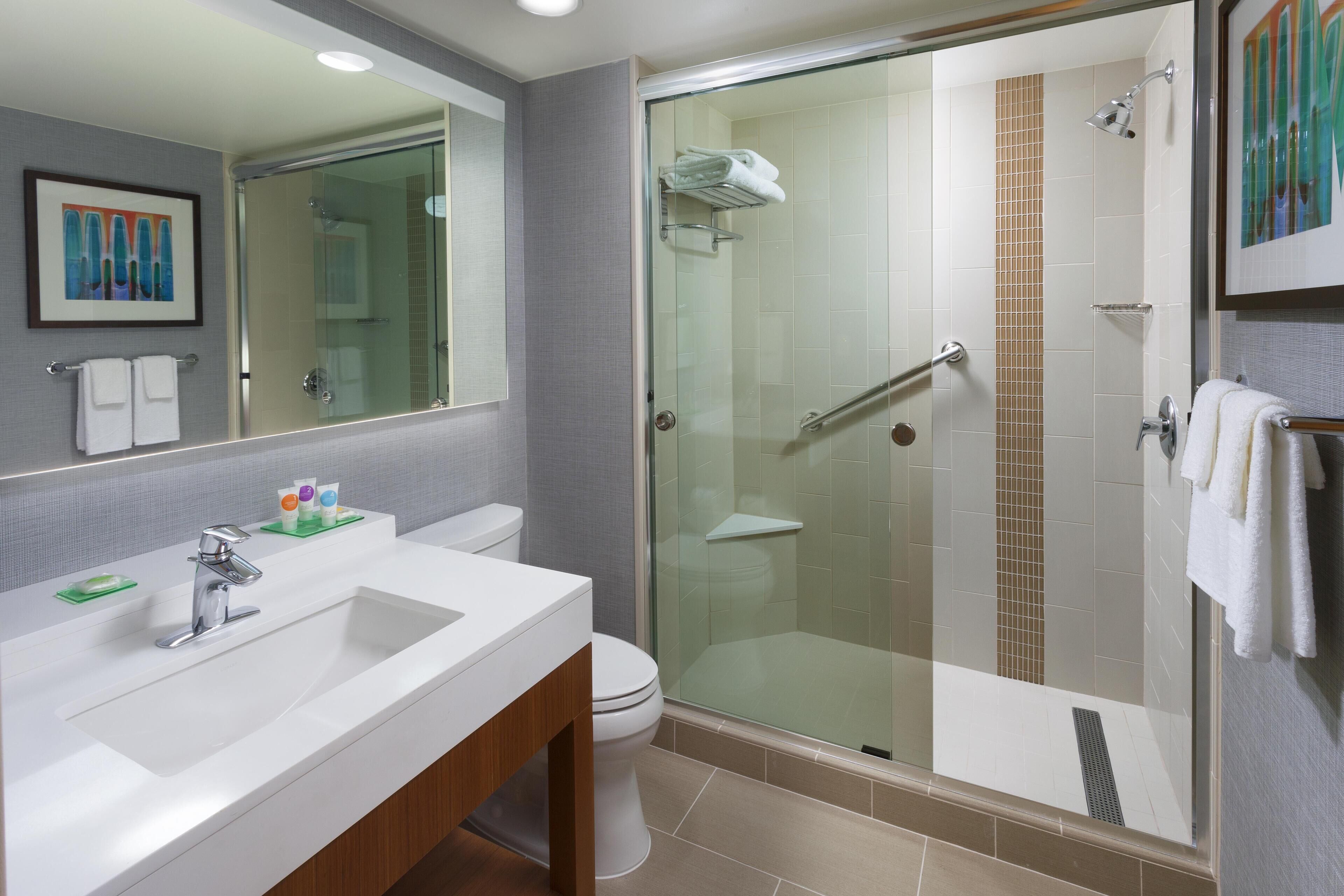 A modern bathroom with a glass-enclosed shower, a white sink, and a large mirror.