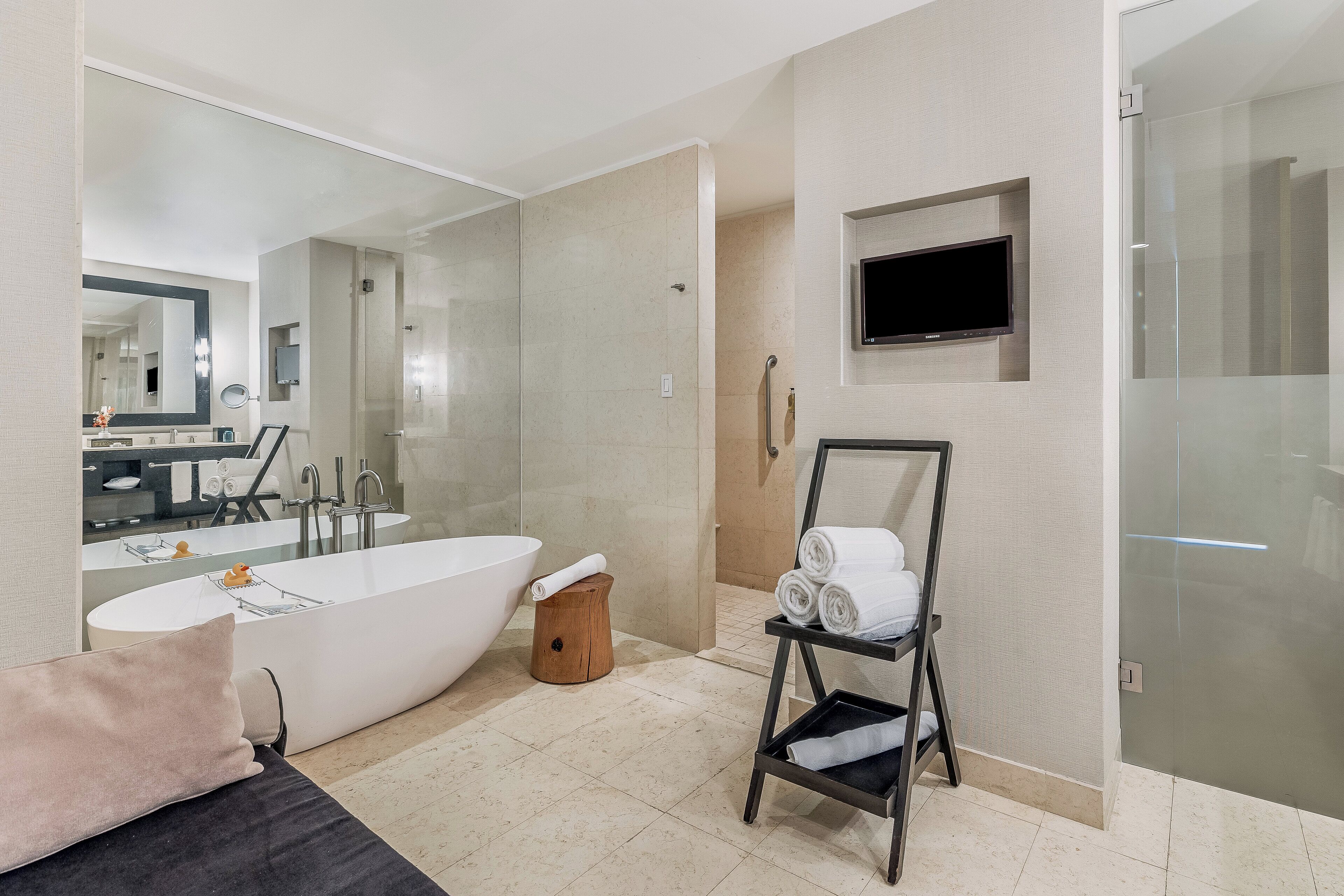 A modern bathroom with a freestanding bathtub, a large mirror, a vanity with a sink, and a glass shower enclosure.