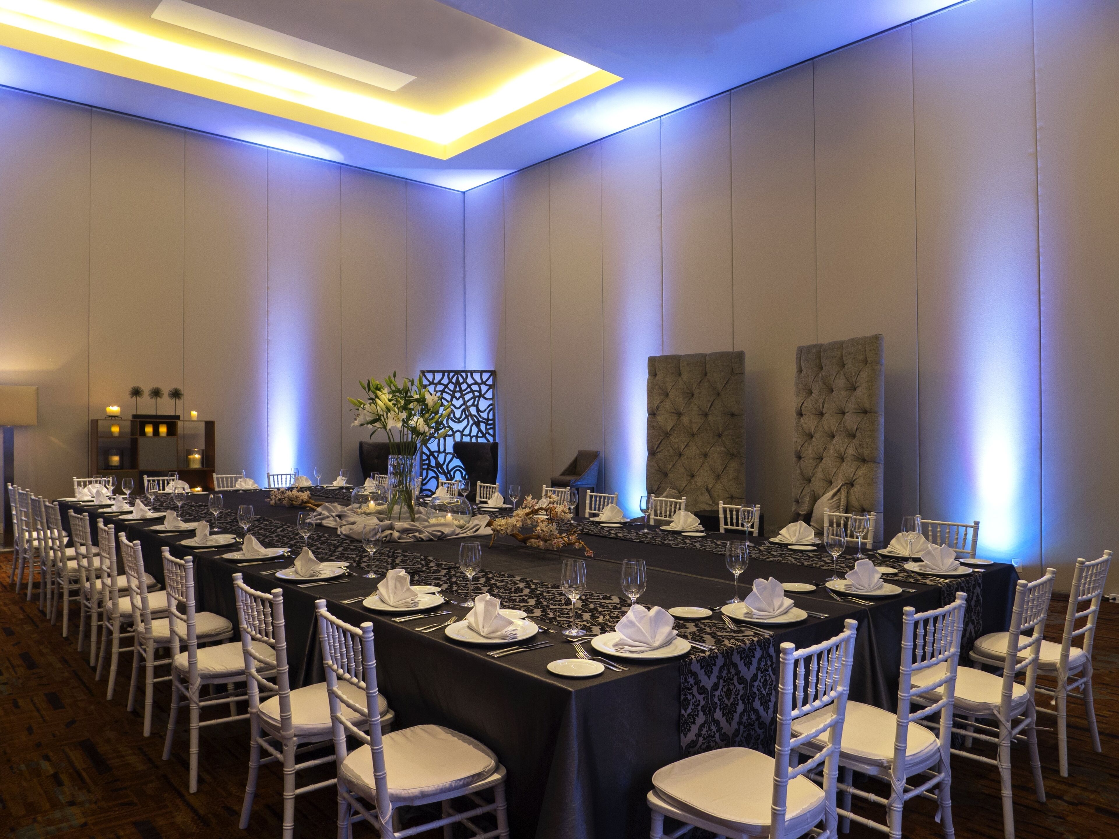 A conference room with long tables, white chairs, and a modern chandelier.