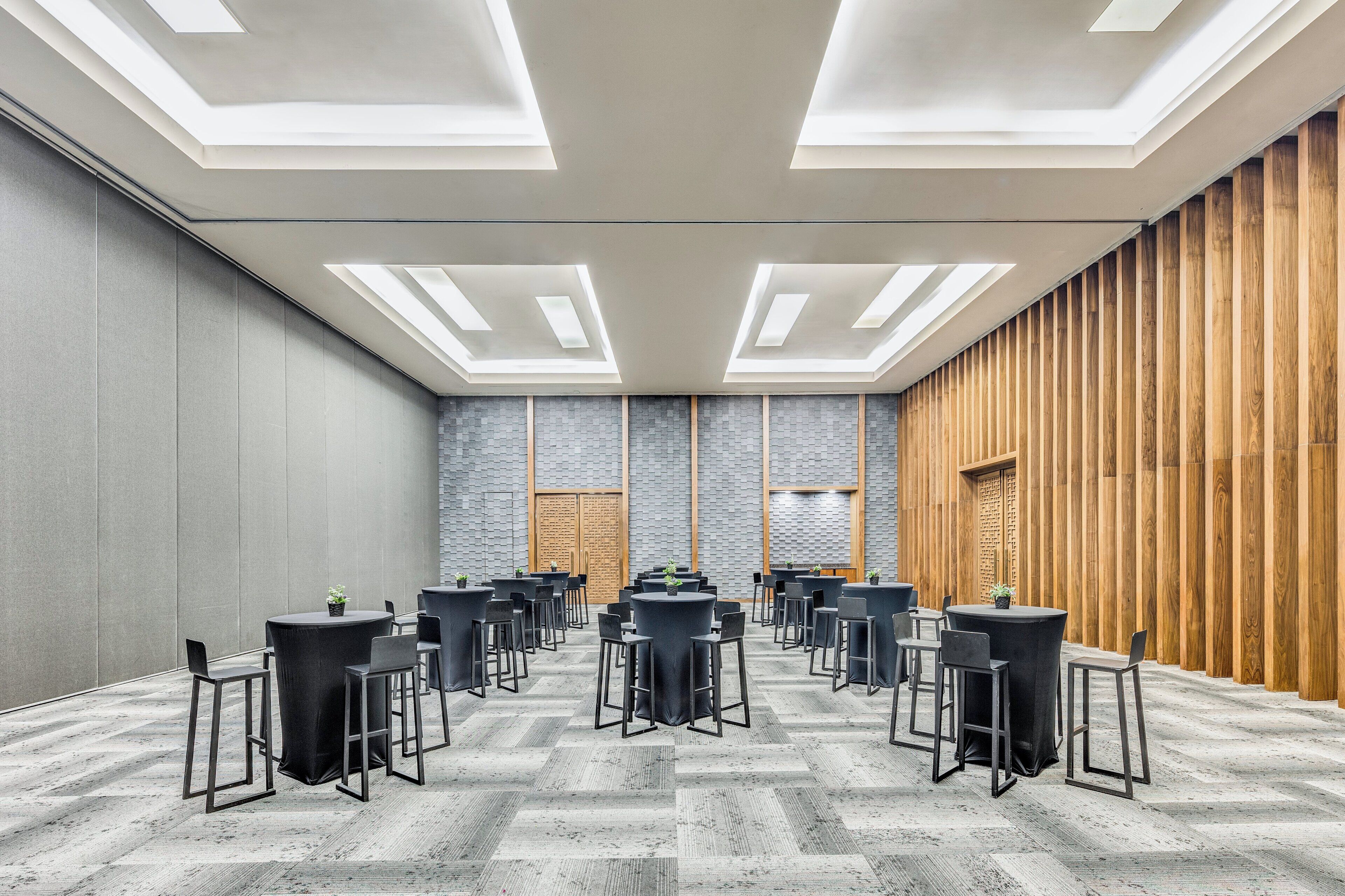 Una sala conferenze con tavoli e sedie rotonde, un pavimento decorato e un pannello di legno a rivestimento.
