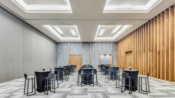 Una sala conferenze con tavoli e sedie rotonde, un pavimento decorato e un pannello di legno a rivestimento.
