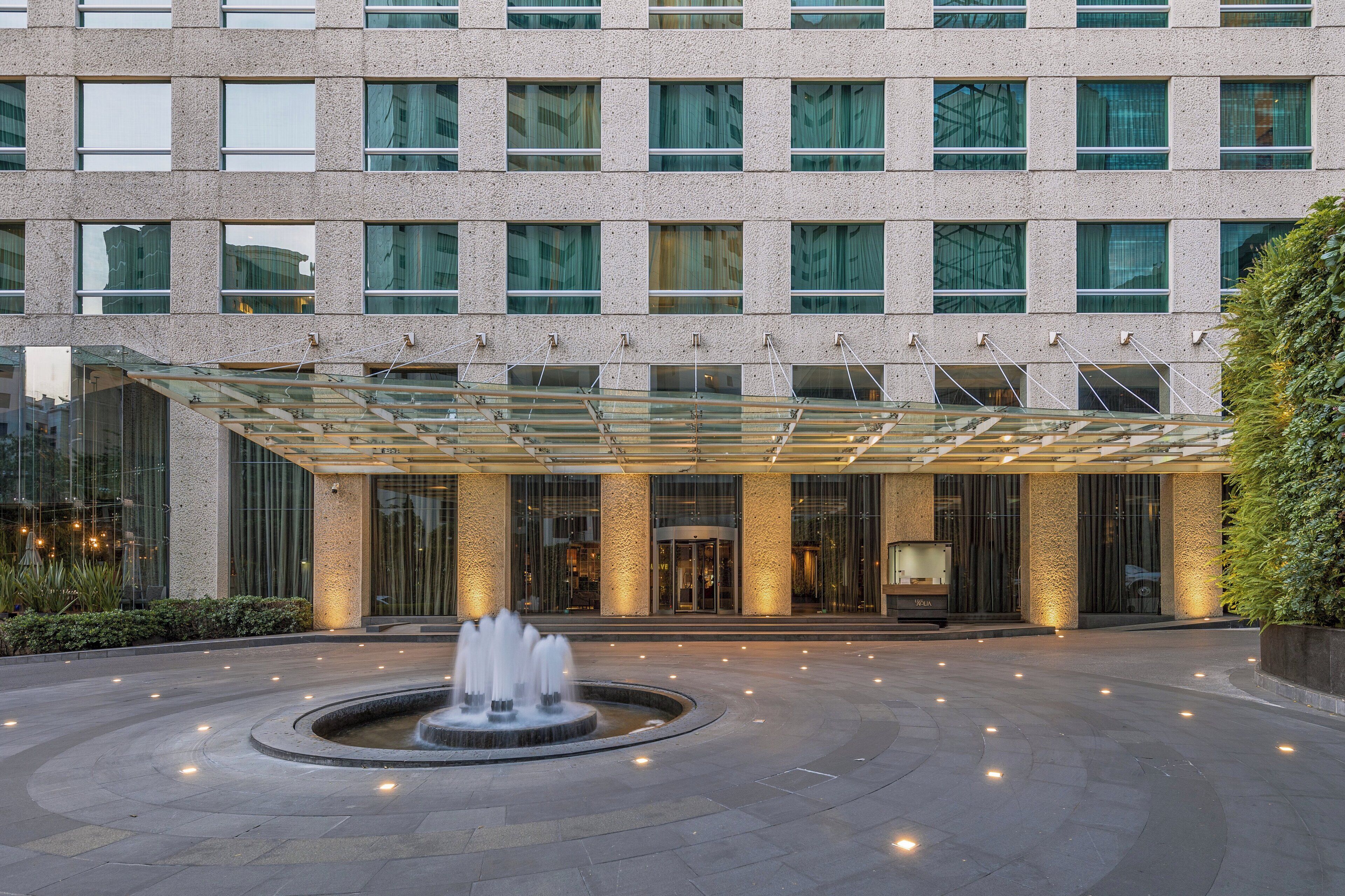 Un hotel moderno con una fuente central, amplios ventanales y una entrada cubierta.