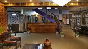 A reception area with a staircase, wooden reception desk, and patterned walls. - Hotel Centre Point (Srinagar)